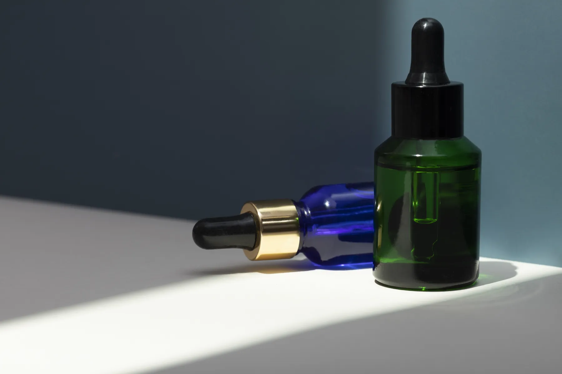 Two glass dropper serum bottles on a dark surface