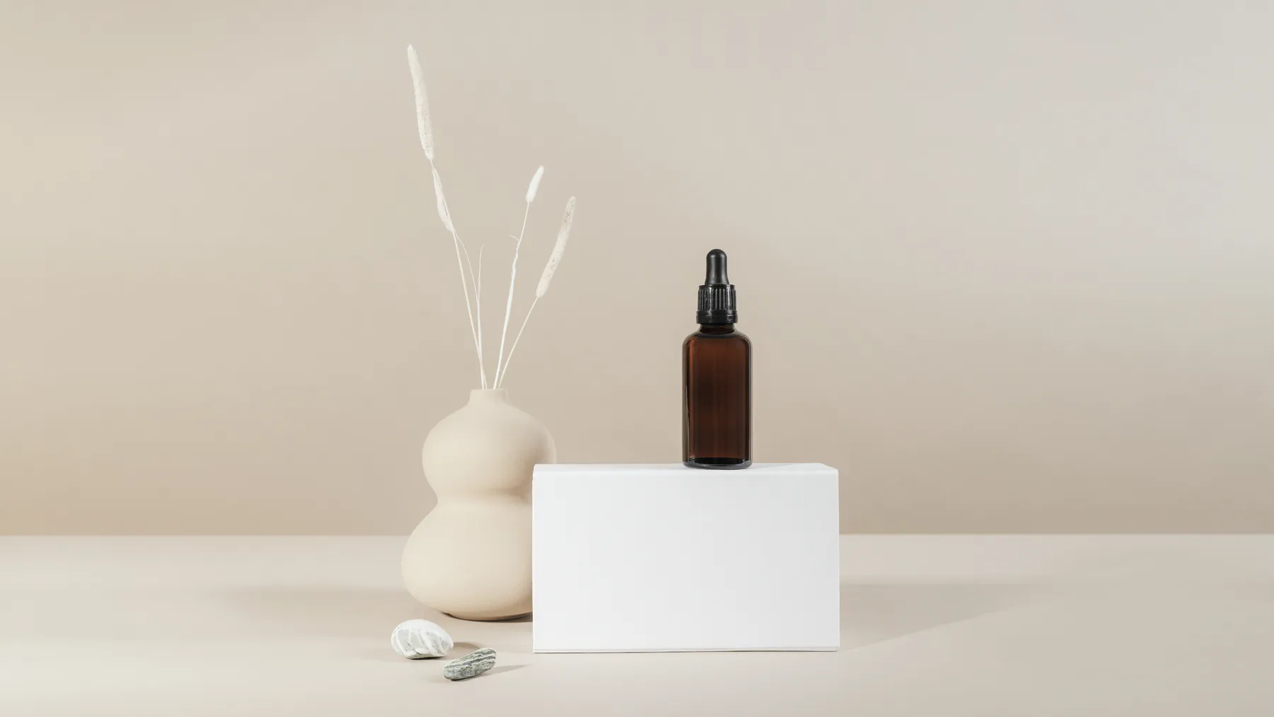 Unlabelled amber glass dropper bottle beside a blank white carton