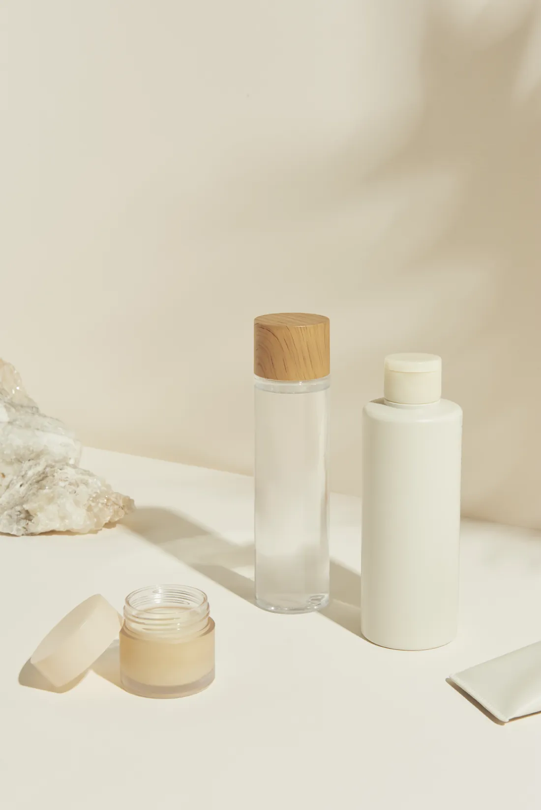 A set of unlabelled skincare bottles, a jar and a tube